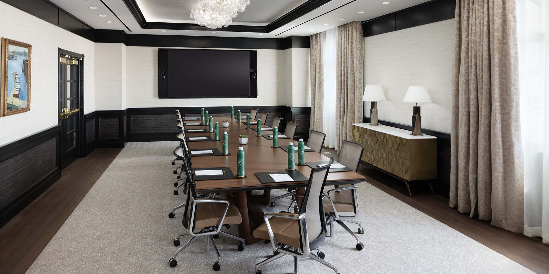 Boardroom with wooden rectangular table, set with water bottles and papers