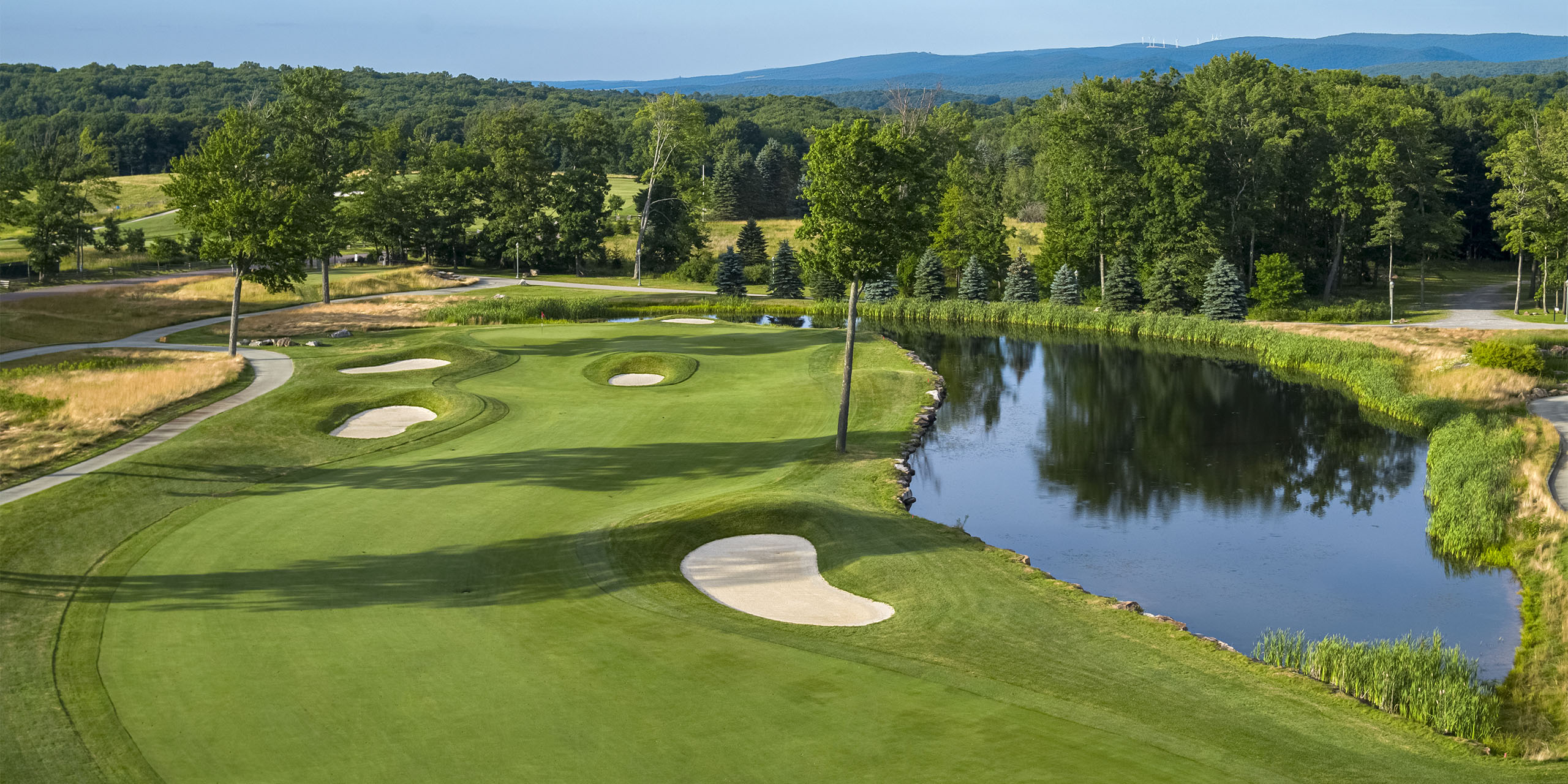 wide view of a golf course with a pond