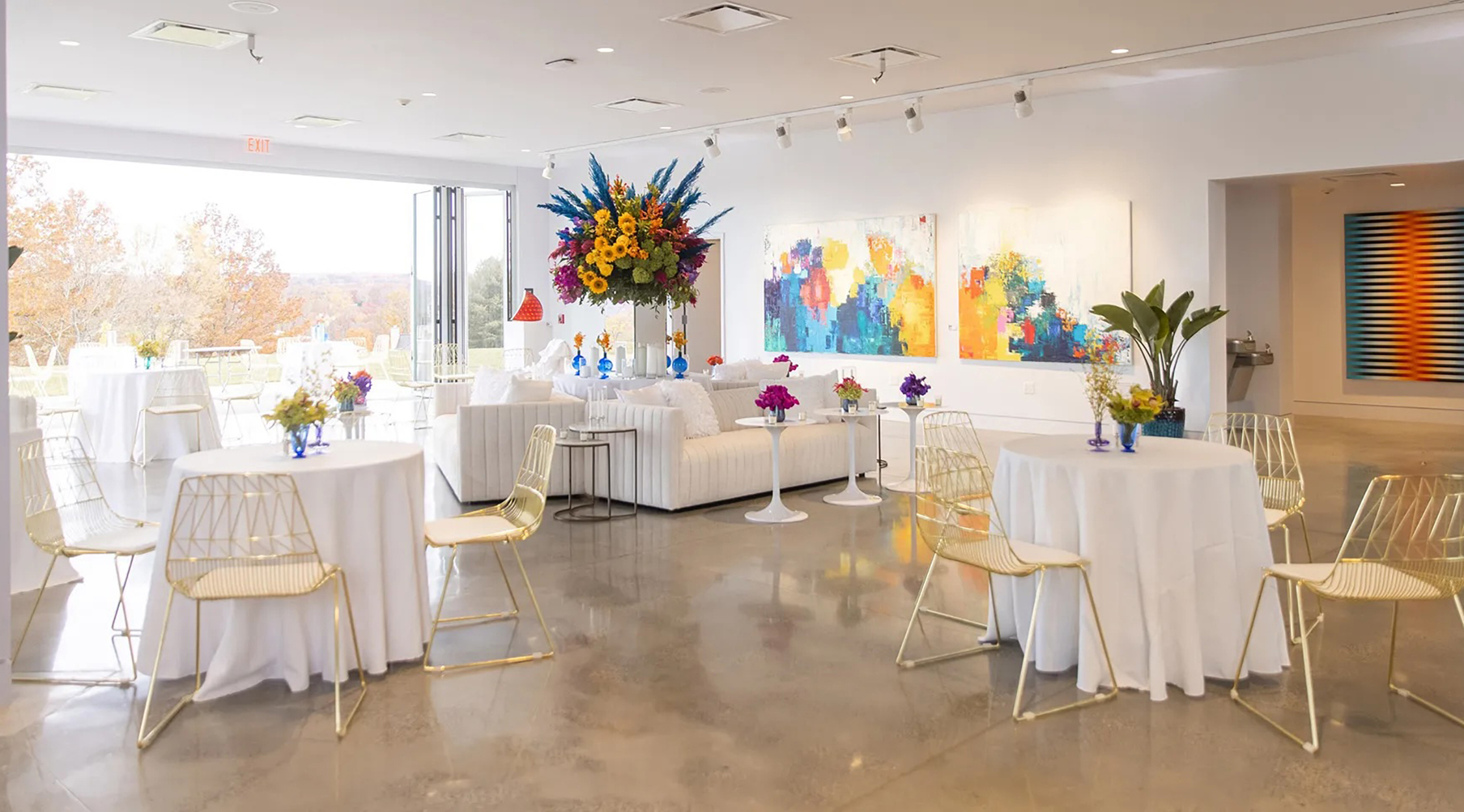 A reception event in Reflections at Nemacolin with large windows and colors of white, blue and yellow as a part of the artwork and decor