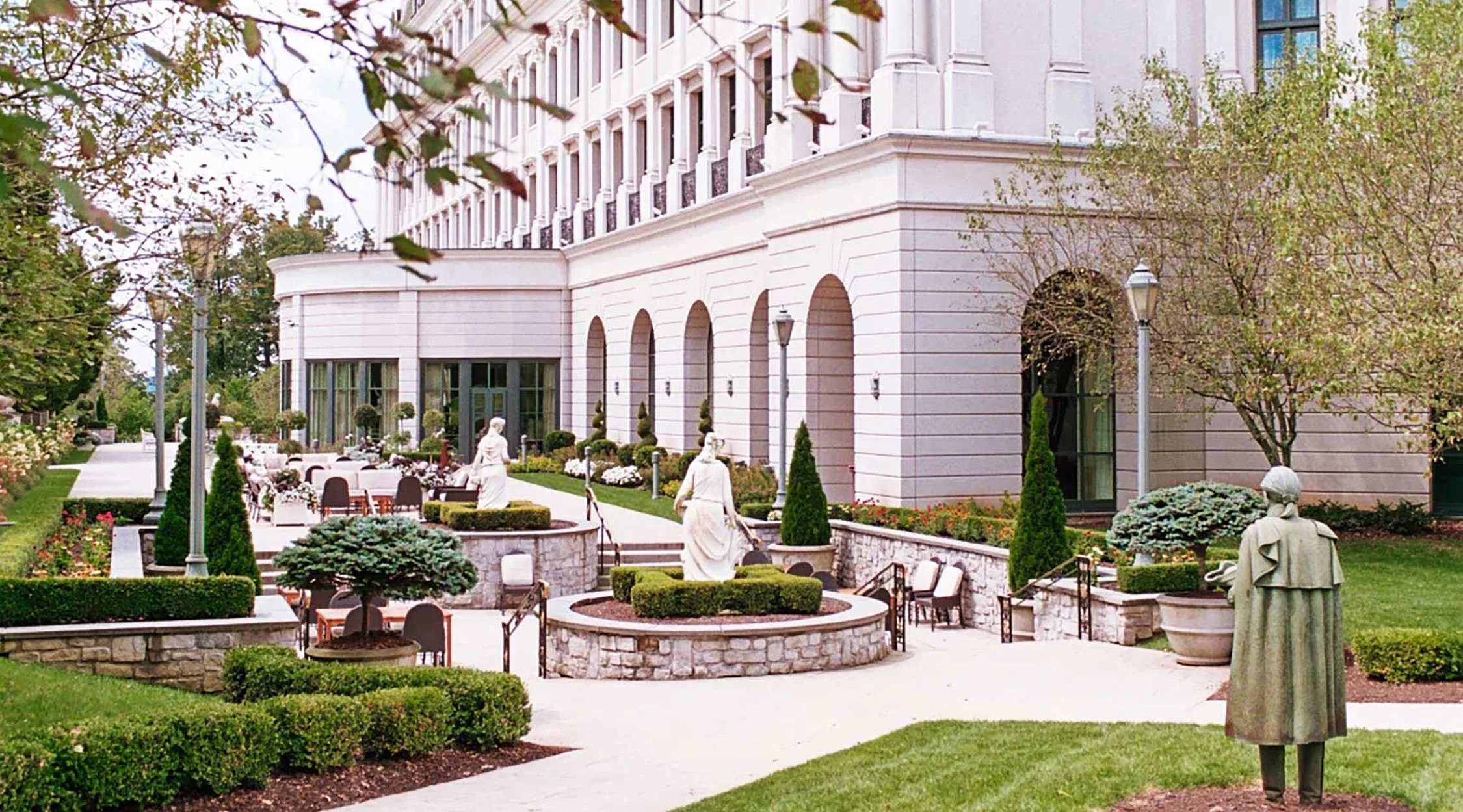 A garden patio, sculptures, and green landscaping, located behind The Chateau hotel at Nemacolin resort